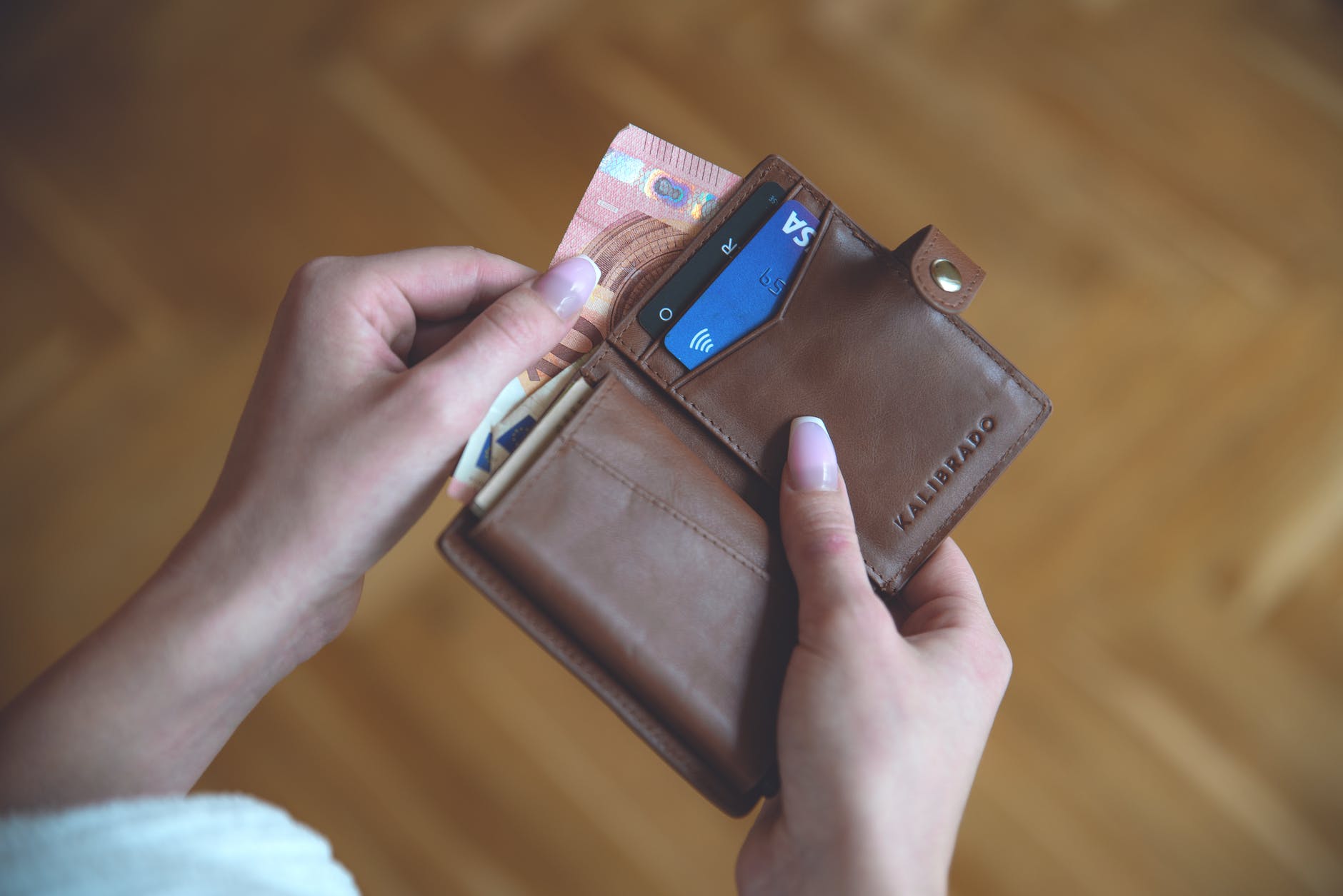 close up shot of a person holding a brown wallet
